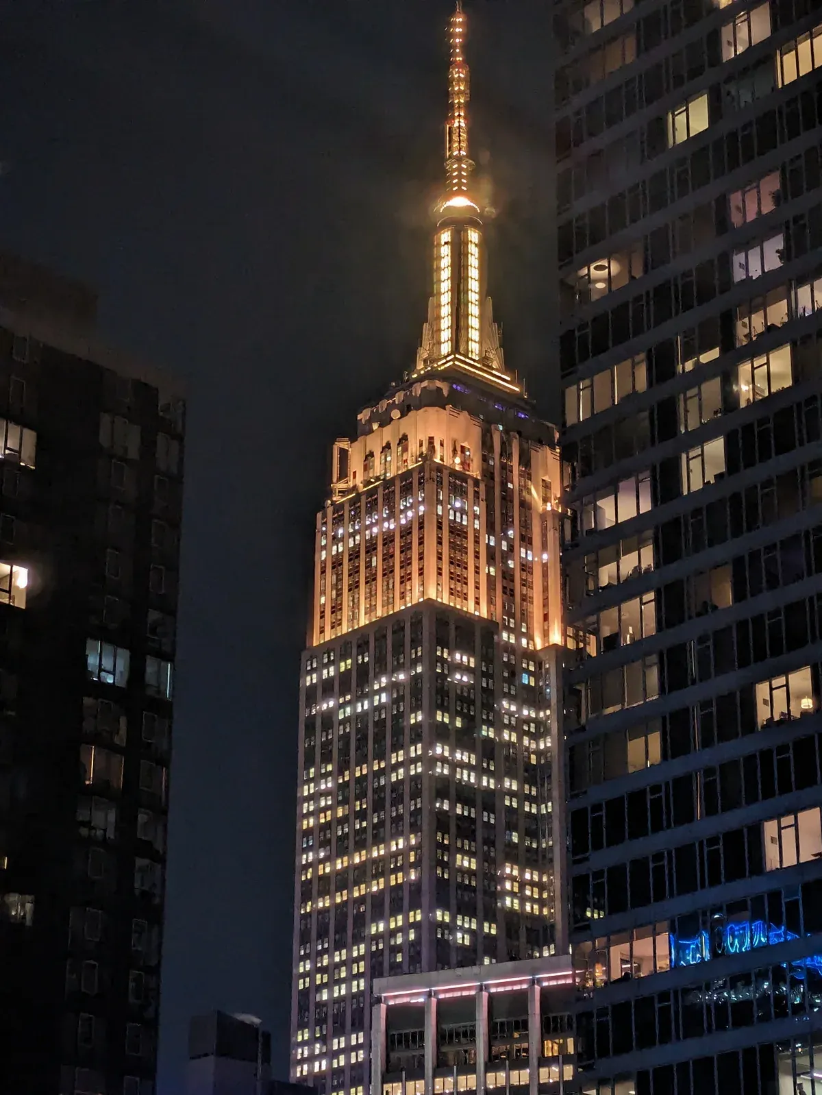 The Empire State Building lit at night above Midtown, passed on every NYC bus tour loop