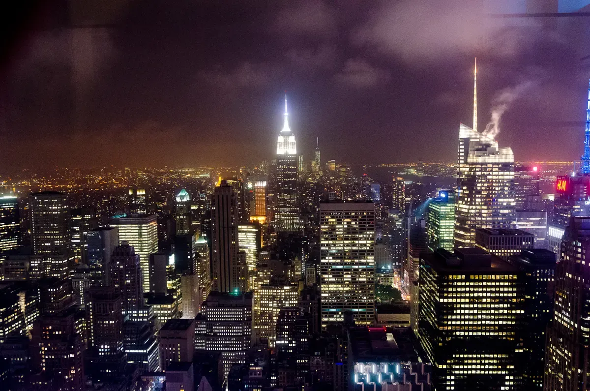 Midtown Manhattan towers lit at night seen from Rockefeller Center, the skyline NYC bus tours ride through by day and night